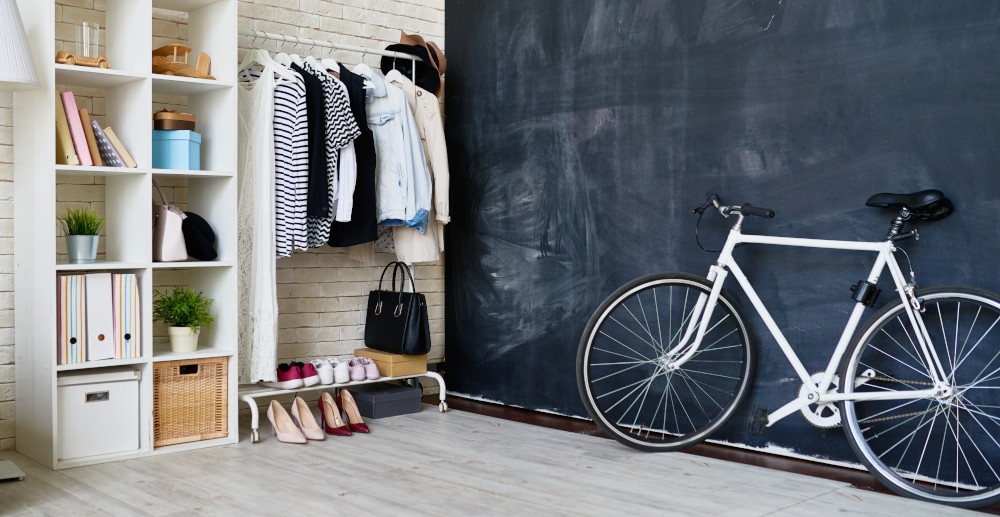 Czarna ściana w pokoju młodzieżowym z wieszakami na ubrania i rowerem